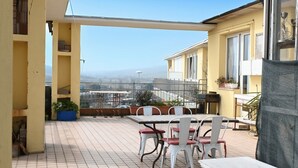 A balcony with a table and chairs, potted plants, and a view of a cityscape. -  P087 - Porto Recanati, exclusive penthouse with panoramic terrace (Porto Recanati)