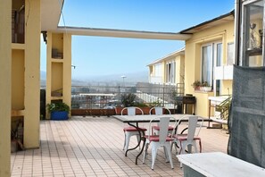 A balcony with a table and chairs, potted plants, and a view of a cityscape. -  P087 - Porto Recanati, exclusive penthouse with panoramic terrace (Porto Recanati)