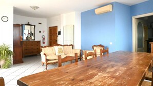 A dining area with a wooden table and chairs, a sofa with a cushion, a mirror, a radiator, and a clock on the wall. -  P087 - Porto Recanati, exclusive penthouse with panoramic terrace (Porto Recanati)