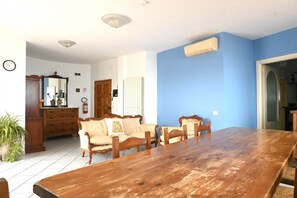 A dining area with a wooden table and chairs, a sofa with a cushion, a mirror, a radiator, and a clock on the wall. -  P087 - Porto Recanati, exclusive penthouse with panoramic terrace (Porto Recanati)