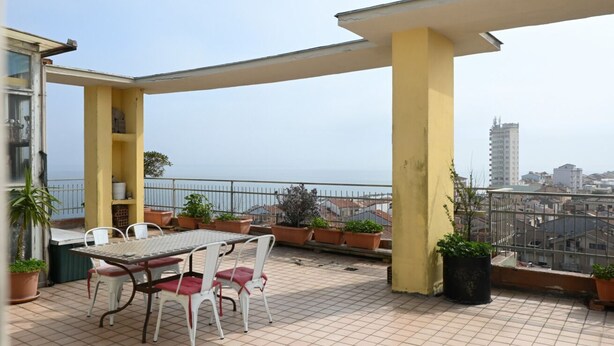 A balcony with a table and chairs, potted plants, and a view of the cityscape. -  P087 - Porto Recanati, exclusive penthouse with panoramic terrace (Porto Recanati)