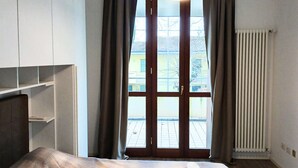 Une chambre d’hôtel avec un lit, une fenêtre avec des rideaux, un radiateur et une vue sur l’extérieur.