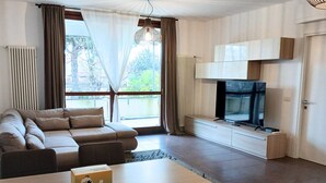 Un salon moderne avec un canapé, un téléviseur et un coin repas.