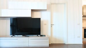 Un salon moderne avec un téléviseur à écran plat, un meuble blanc et une porte.