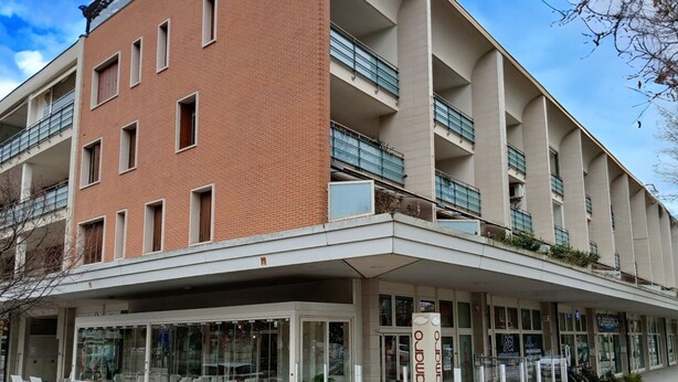 Un hôtel à plusieurs étages, doté d’une façade en briques, de balcons et d’un espace d’entrée abrité.