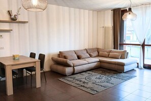 Una sala de estar con un sofá, una mesa de comedor, sillas y una alfombra.
