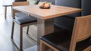 Ein moderner Essbereich mit einem Holztisch, schwarzen Polsterstühlen und einer Pendelleuchte.