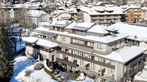 Ein modernes Hotel mit mehreren Etagen, Balkonen und Blick auf schneebedeckte Berge.