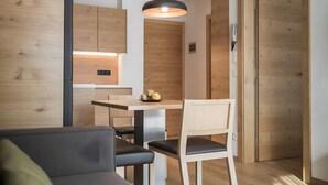 Eine moderne Küche mit Holzausstattung, einem Essbereich mit Tisch und Stühlen sowie einem Sofa im Vordergrund.