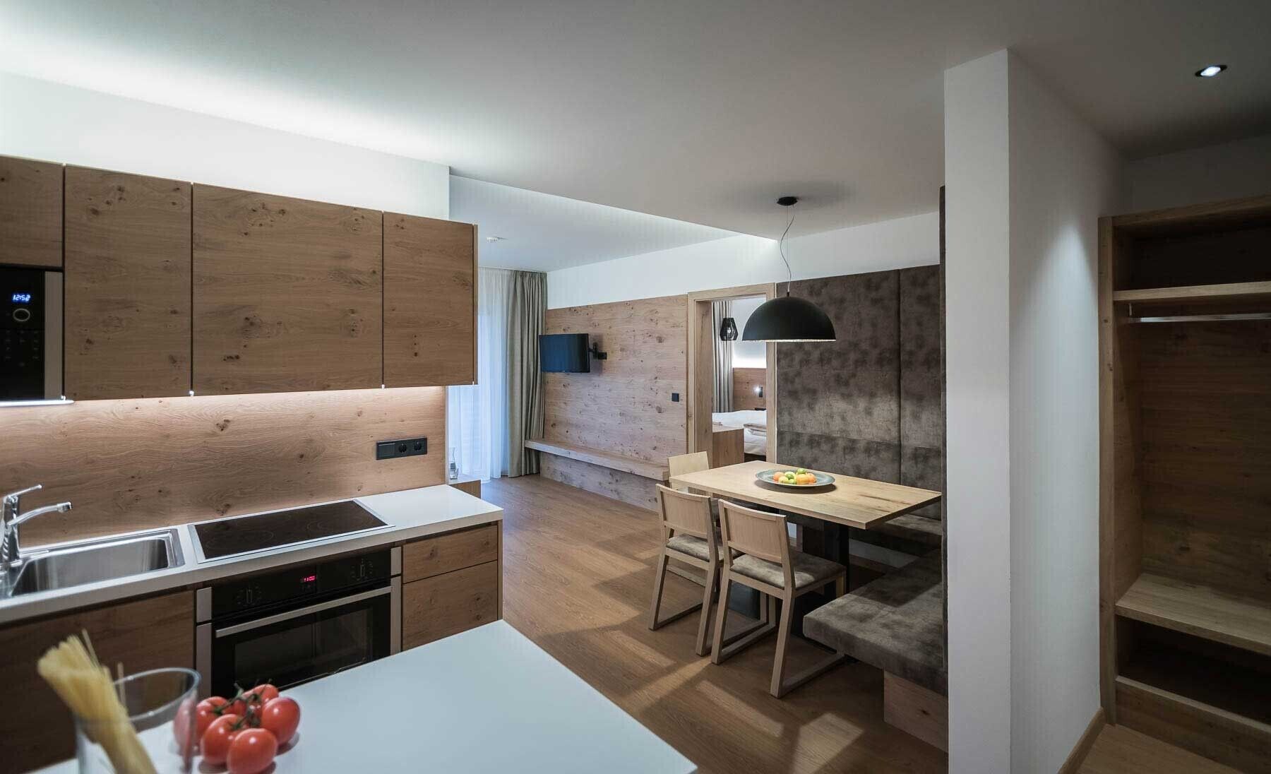 Eine moderne Küche mit Holzausstattung, einem eingebauten Backofen und einem Essbereich mit Tisch und Stühlen.