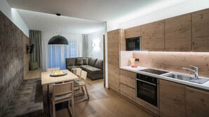 Une cuisine compacte avec des meubles en bois, un four encastré et un coin repas comprenant une table et des chaises.