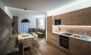 Une cuisine compacte avec des meubles en bois, un four encastré et un coin repas comprenant une table et des chaises.