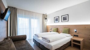 A hotel room with a bed, a TV, a nightstand, and a couch.