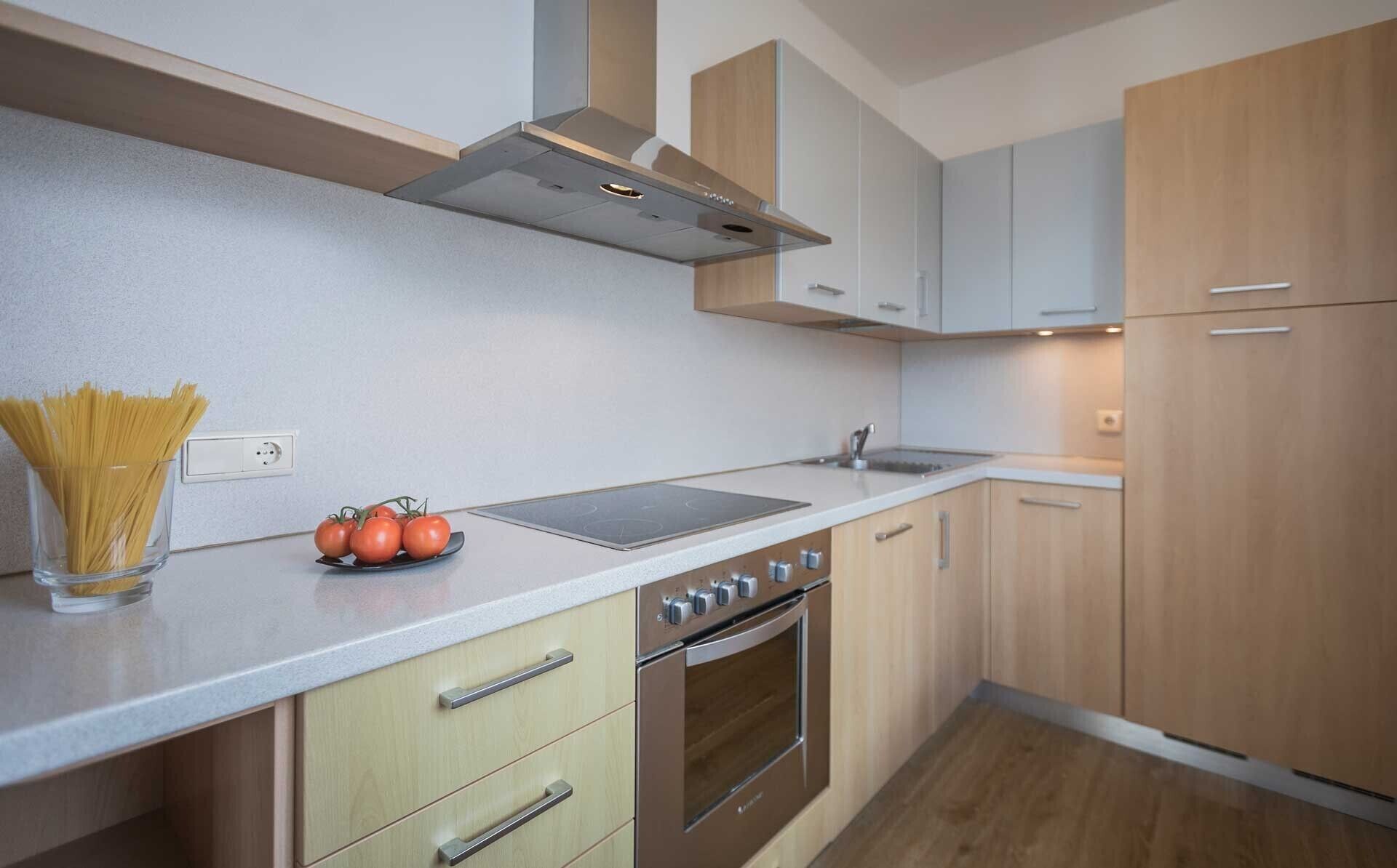 A modern kitchen with a built-in oven, a stovetop, and wooden cabinets.