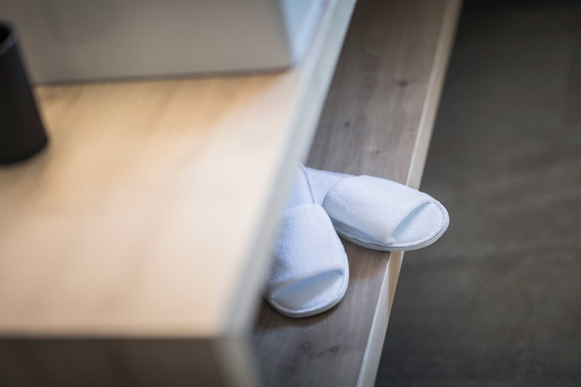 Et par hvide slippers på en træbænk.