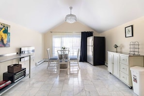 A kitchen with a dining table, chairs, a refrigerator, and a microwave.