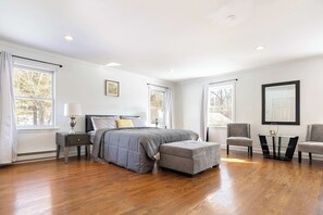 A bedroom with a bed, nightstand, chair, ottoman, and a table with a lamp. - Spacious Easton 2BR Townhouse with Big Yard (Easton)