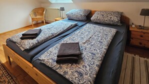 Une chambre à coucher avec un lit, une lucarne, une chaise, une lampe et une table de chevet.