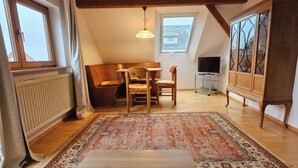 Une pièce de style loft avec un plafond haut, une table à manger avec des chaises, un téléviseur et un meuble.