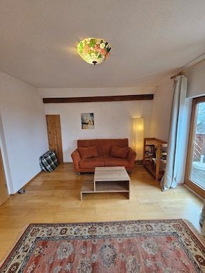 Sala de estar com sofá, mesa de centro, tapete, quadro e luminária no teto.