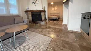 A living room with a fireplace, sofa, coffee table, and a TV mounted on the wall. - Sunrise Beach Front Villa (Nea Propontida)