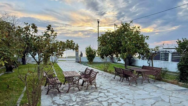 A courtyard with stone flooring, benches, and trees. - Sunrise Beach Front Villa (Nea Propontida)