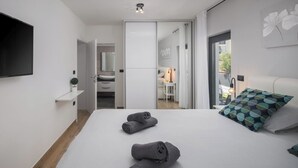 Habitació d'hotel moderna amb un llit gran, un televisor de pantalla plana, un taulell petit i vista exterior.