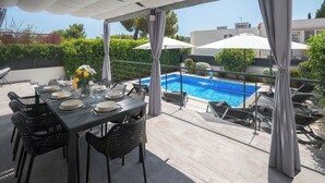 Terrassa al terrat amb piscina, taula de dinar preparada amb plats i gots, i mobles de jardí.