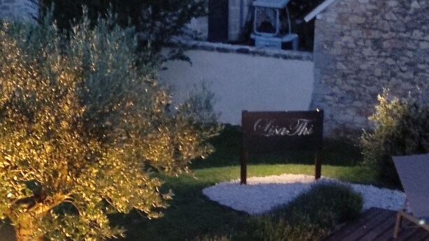 A wooden deck with a bench, a sign reading 'Casa The', and a stone building in the background. - Lili de la Lisathi (Palmas d'Aveyron)