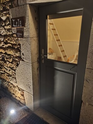 A stone wall with a door, a staircase, and a sign with the name 'Lili.' - Lili de la Lisathi (Palmas d'Aveyron)