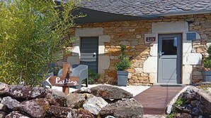A stone building with a sign indicating parking, a door, and a small potted plant. - Lili de la Lisathi (Palmas d'Aveyron)