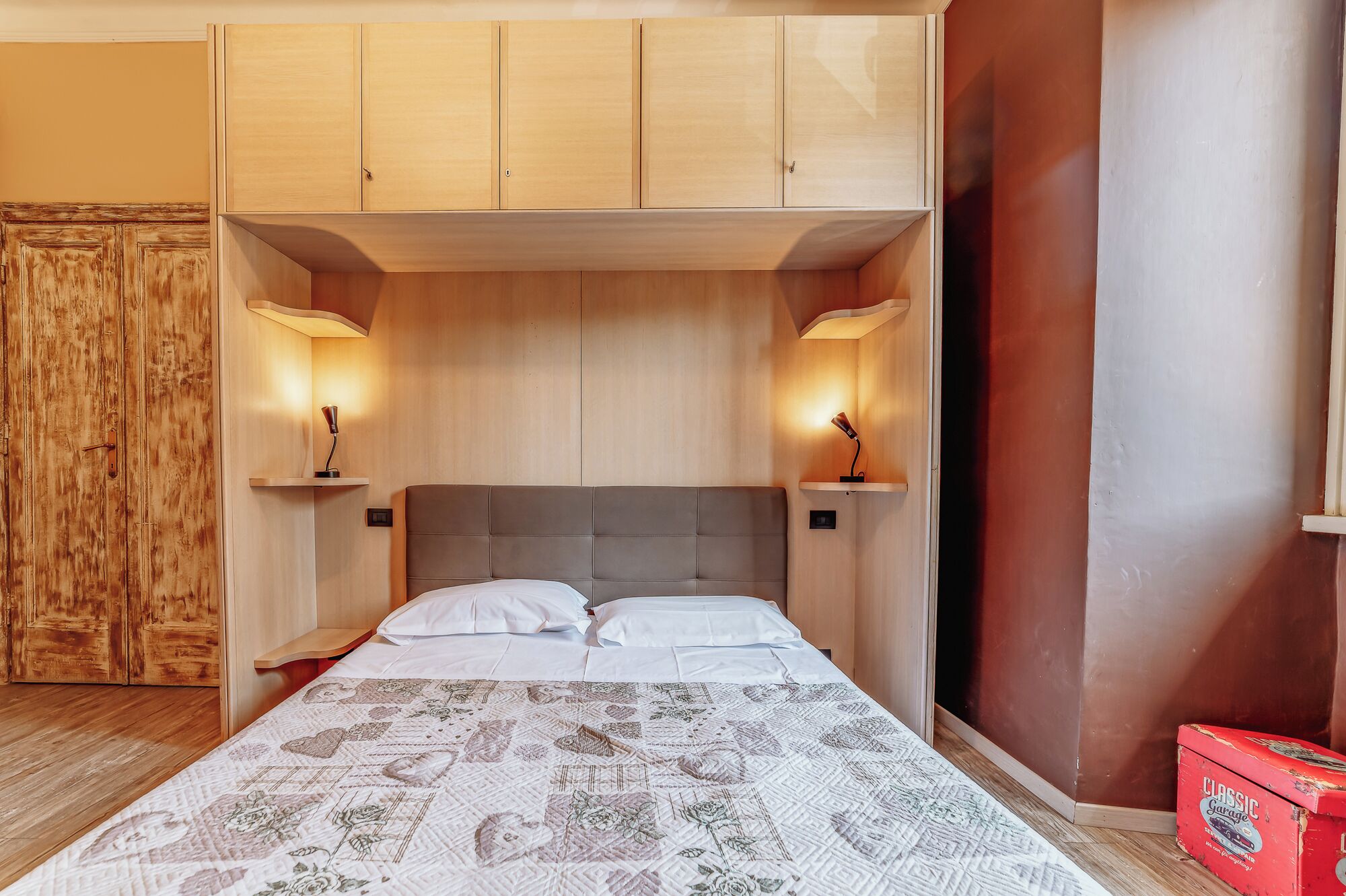 Une chambre à coucher avec un lit, une armoire en bois et deux lampes de chevet.