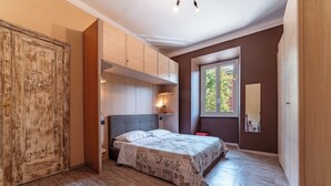 A bedroom with a bed, wooden wardrobe, and a window with a view. - Claudio Flat - Metro Re di Roma (Rome)