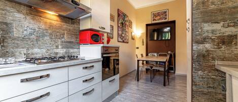 A modern kitchen with a gas stove, a red microwave, and a dining area with a wooden table and chairs.
