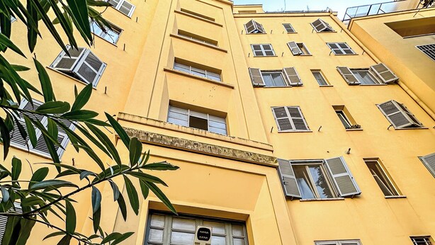 A yellow building with a large entrance door labeled 'E' and multiple windows. - Claudio Flat - Metro Re di Roma (Rome)