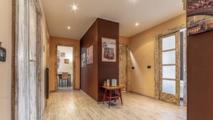 A hallway with wooden flooring, a dining area with chairs, a table, and a clock. - Claudio Flat - Metro Re di Roma (Rome)