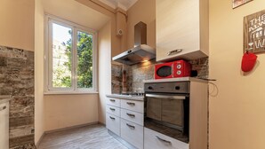 A compact kitchen with a window, a stove, a microwave, and a built-in oven. - Claudio Flat - Metro Re di Roma (Rome)