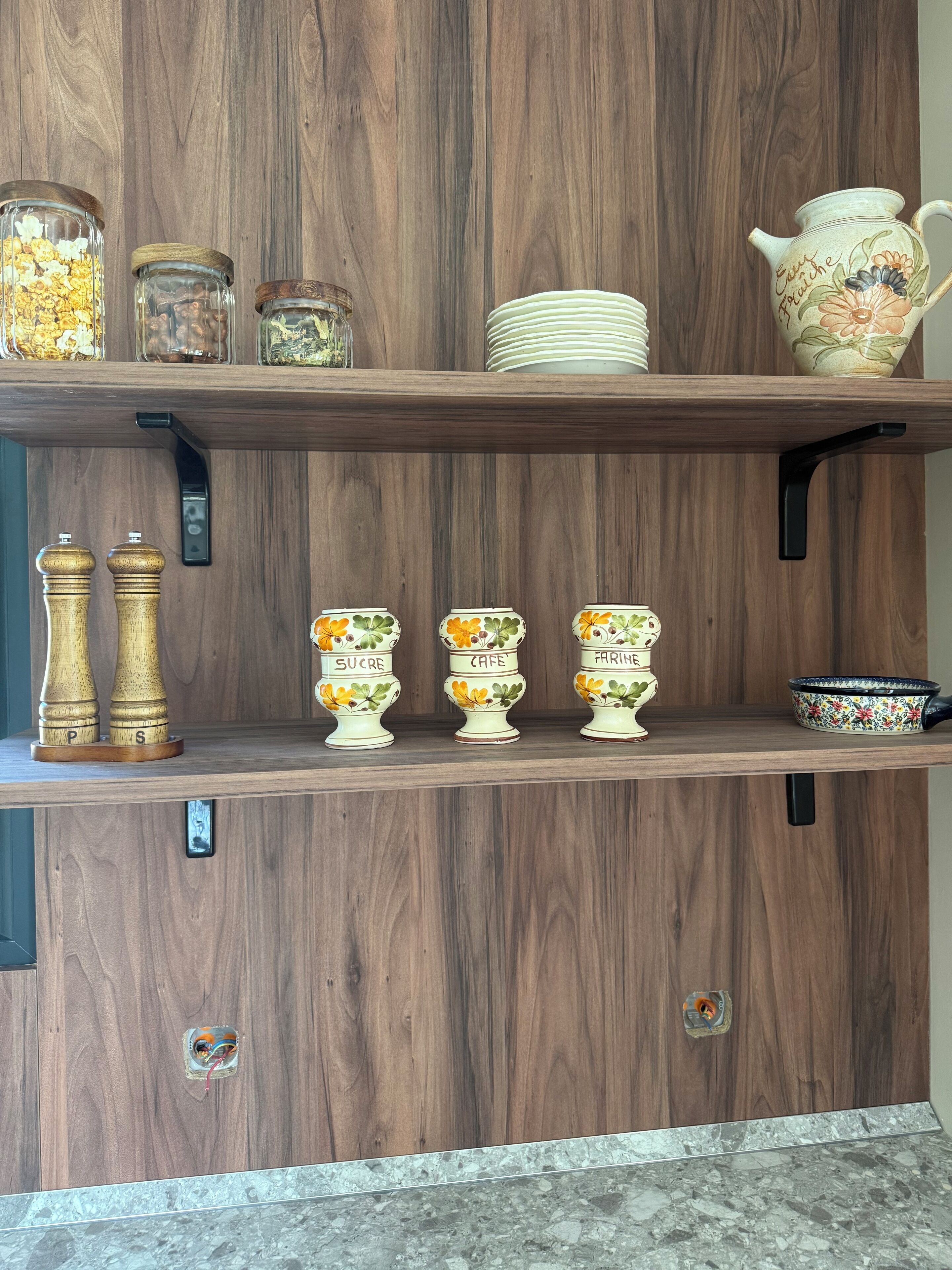Wooden shelves with jars, a pepper mill, and decorative items.