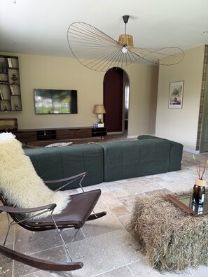 A modern living room with a sectional sofa, a rocking chair, a fireplace, and a large window. - Charming house with swimming pool close to beaches and rivers  (Canavaggia)