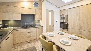 Een moderne keuken met houten kastjes, een ingebouwde magnetron en een eettafel voor vier personen.