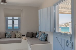 Ein Zimmer mit einer Couch, einem Fenster mit Meerblick und einer Tür mit Meerblick.