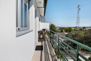 Un balcone con tavolo e sedie, ringhiera verde e vista sulla campagna circostante.