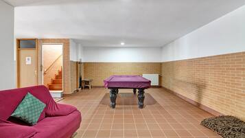 A room with a red sofa, a covered table, and a staircase leading to an upper floor.
