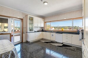 Une cuisine moderne avec des armoires blanches, un comptoir en granit et une vue sur l’extérieur.