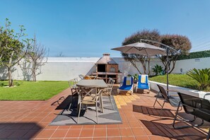 Une terrasse avec un barbecue, des sièges d’extérieur et une vue sur le ciel.