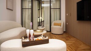 Ein modernes Wohnzimmer mit einer Couch, einem kleinen Tisch mit einer Serviertablett voller Snacks, einem Fernseher und einer Glastür zum Balkon.