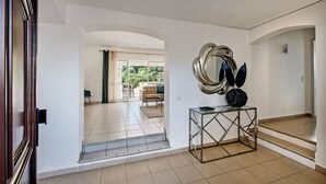 Un pasillo amplio con vistas a una sala de estar, una escalera y un espejo decorativo sobre una consola.