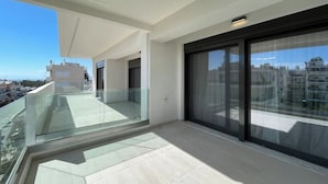 Een modern balkon met glazen hekwerk, een helder uitzicht op de stadsgezichten, en een betegelde vloer.