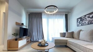 Een moderne woonkamer met een bank, een salontafel, een televisie en een schilderij aan de muur.