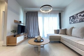 Ein modernes Wohnzimmer mit einer Couch, einem Couchtisch, einem Fernseher und einem Bild an der Wand.